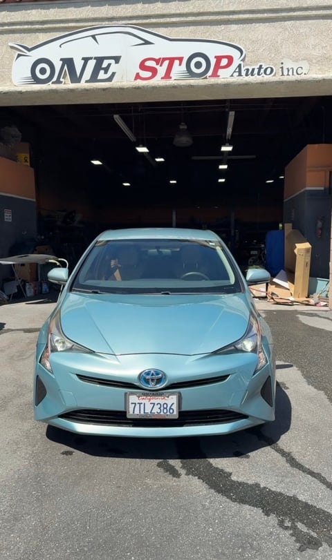 Light blue Toyota Prius parked in front of One Stop Auto Inc. garage with storefront signage visible