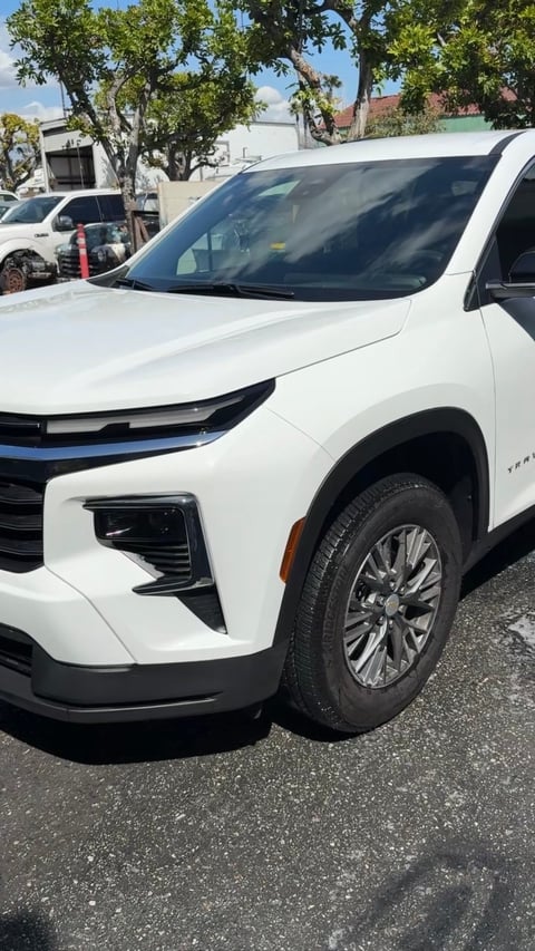 White Chevrolet SUV parked in a lot with trees and buildings in the background