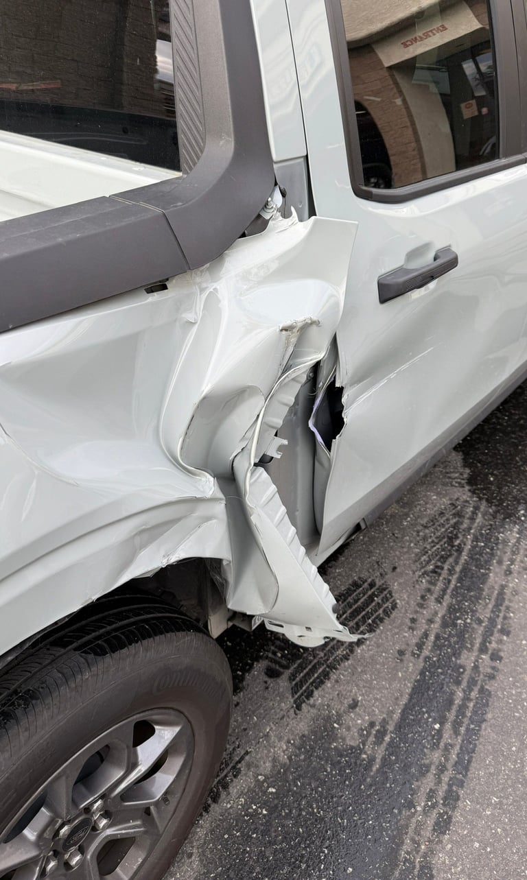 White van with severe damage to the drivers side door and panel, dented and crushed from impact