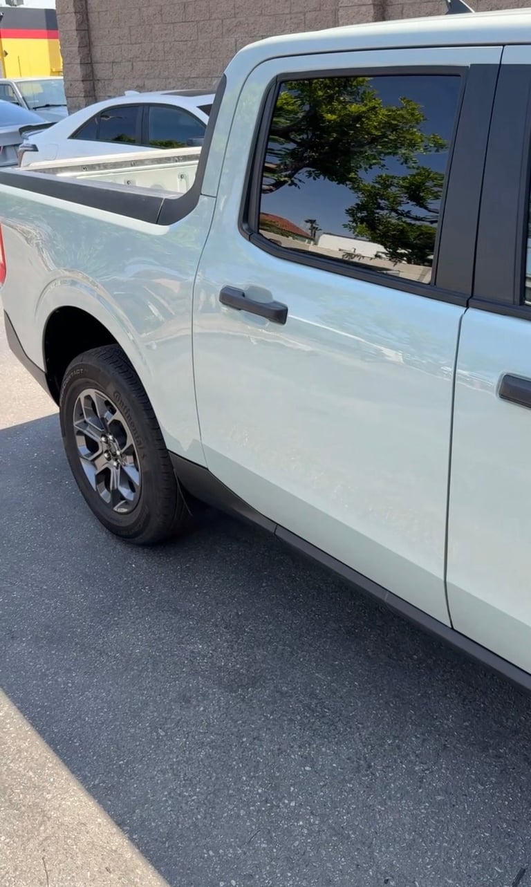 White pickup truck parked in a lot, showing the side profile with tinted windows and alloy wheels